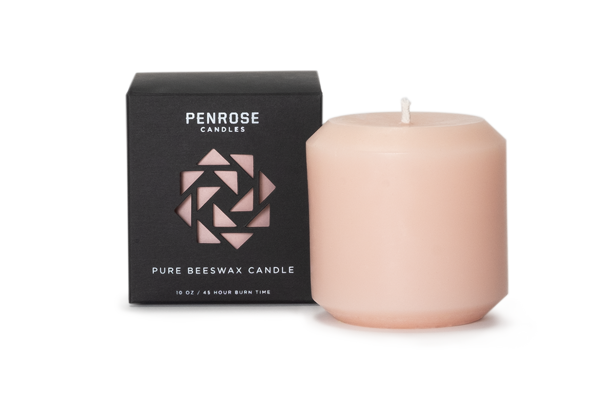 A pink 3 inch pillar candle made from pure beeswax, displayed alongside its black packaging with the brand name 'Penrose' and the product name 'Pillar Candle' in minimalist design.